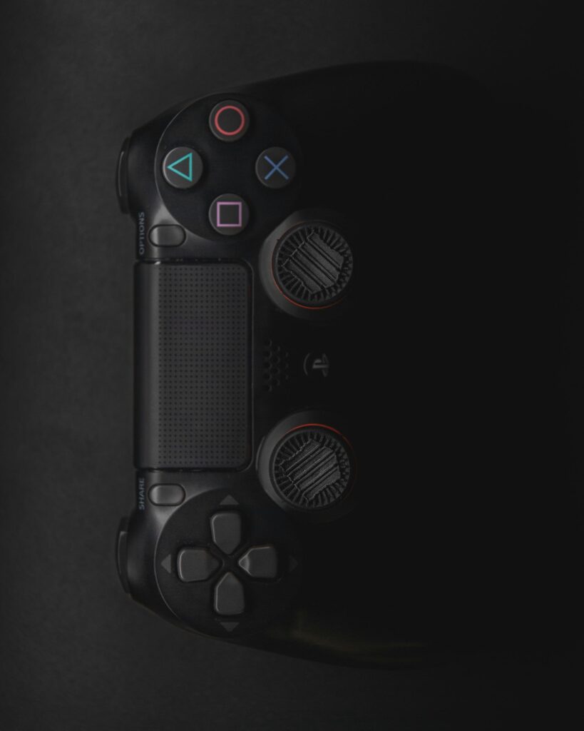 Moody close-up of a black gaming controller in low light with colorful buttons.